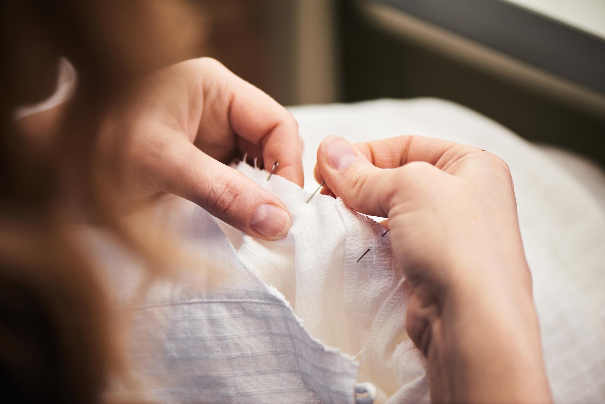 Mani che ricamano con ago e filo su lino pregiato